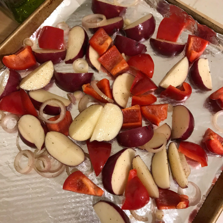 raw potatoes, onions, and red peppers on baking sheet