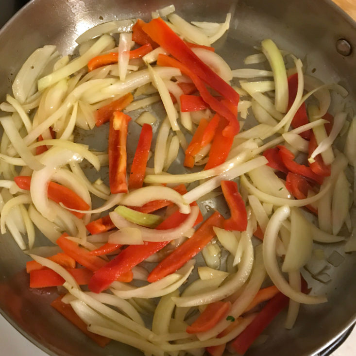 sliced onions and peppers sauteing in pan
