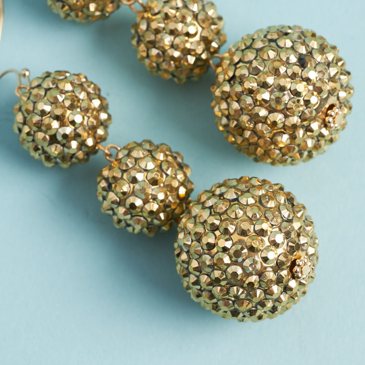 close up of long dangling ball-shaped earrings