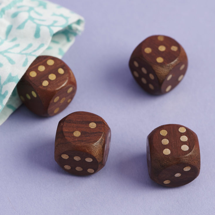 set of four wooden and brass dice coming out of pouch