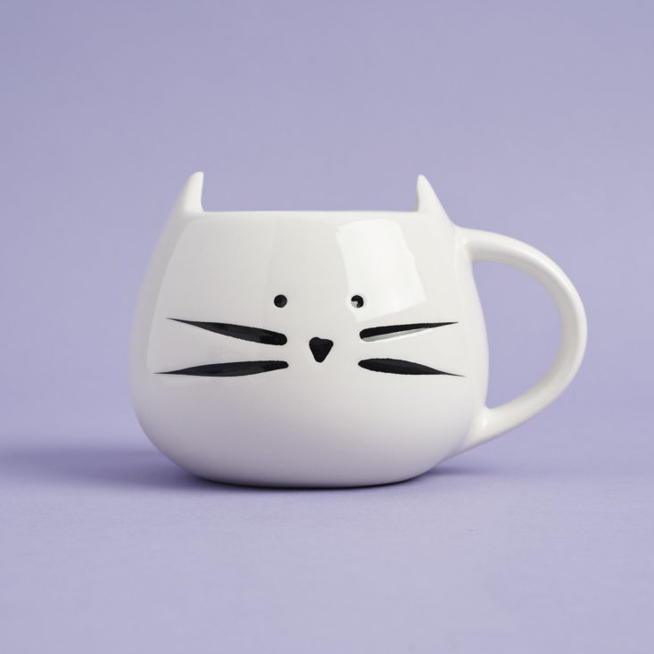 the front of a white mug that looks like a cat's head with a black cat face on it