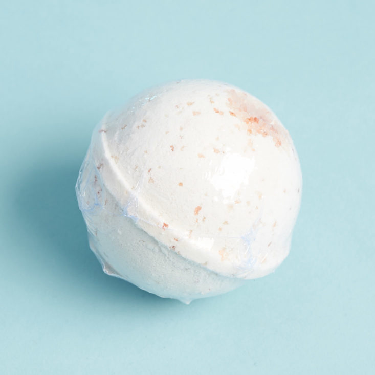 white bath bomb with peach sprinkles in plastic wrap