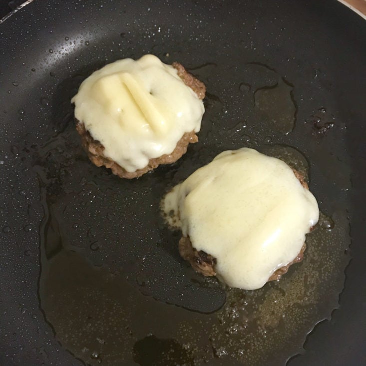 melted cheese on burgers in pan
