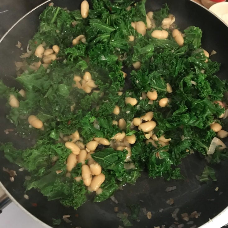 kale and beans cooking in pan with demi-glace verjus and red pepper flakes