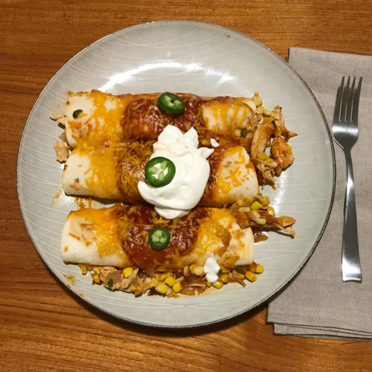 plated Adobo Chicken Enchiladas with jalapeño pepper and sour cream
