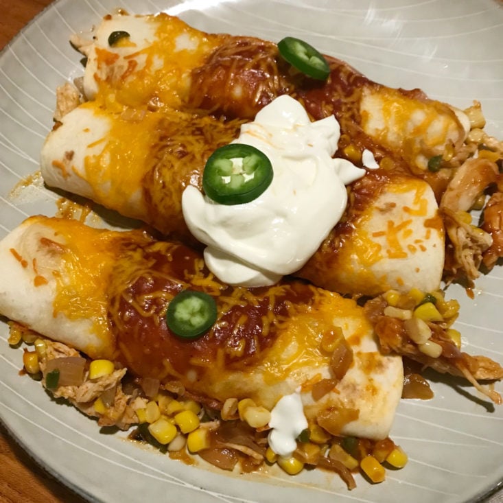 close up of Adobo Chicken Enchiladas with jalapeño pepper and sour cream