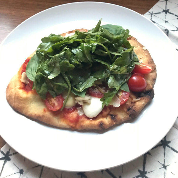 close up of finished Neapolitan Pizza Margherita with arugula salad and basil