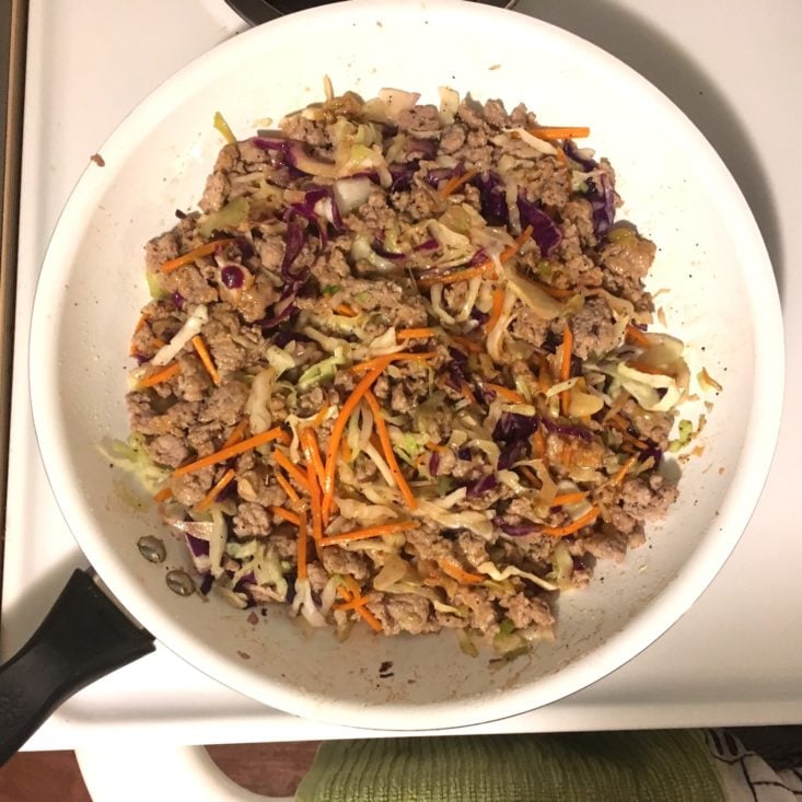 ground pork and slaw mixed together in a large white skillet with ponzu sauce